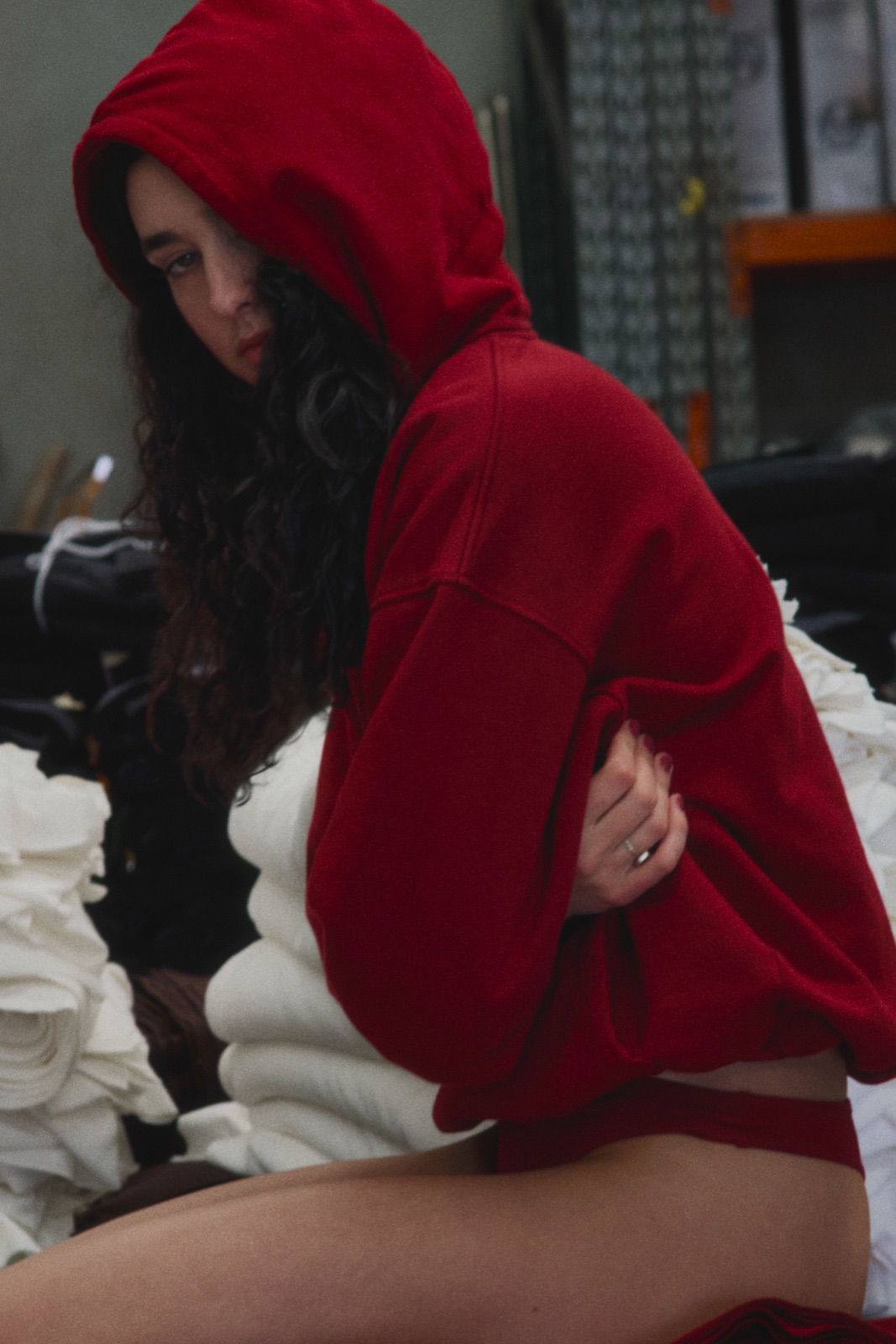 Katja in a red hoodie sitting among bales of white fabric, photographed by Eli Samuel for Australian Stitch.