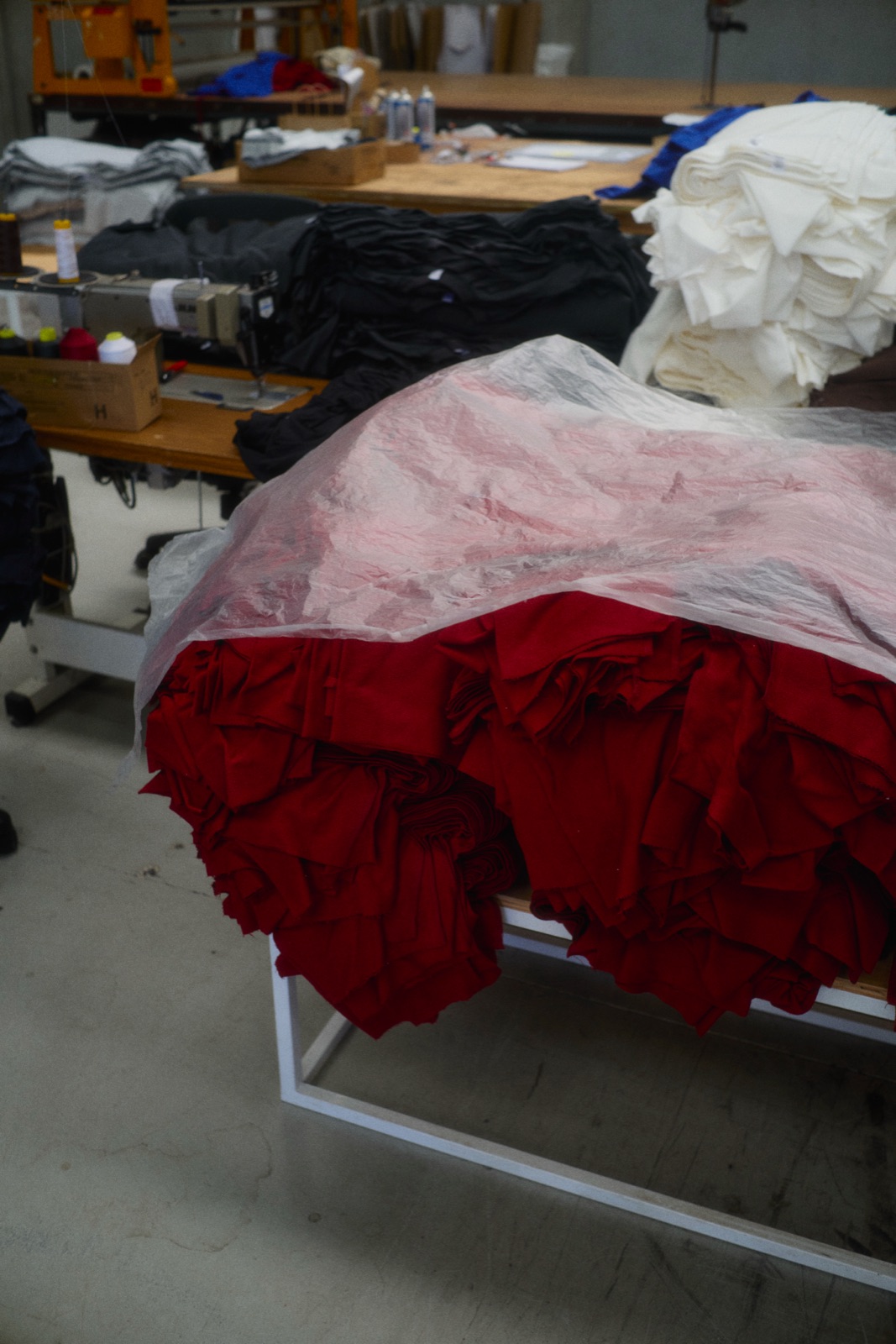 Red fabric spilling out of plastic on a factory table, photographed by Eli Samuel for Australian Stitch.