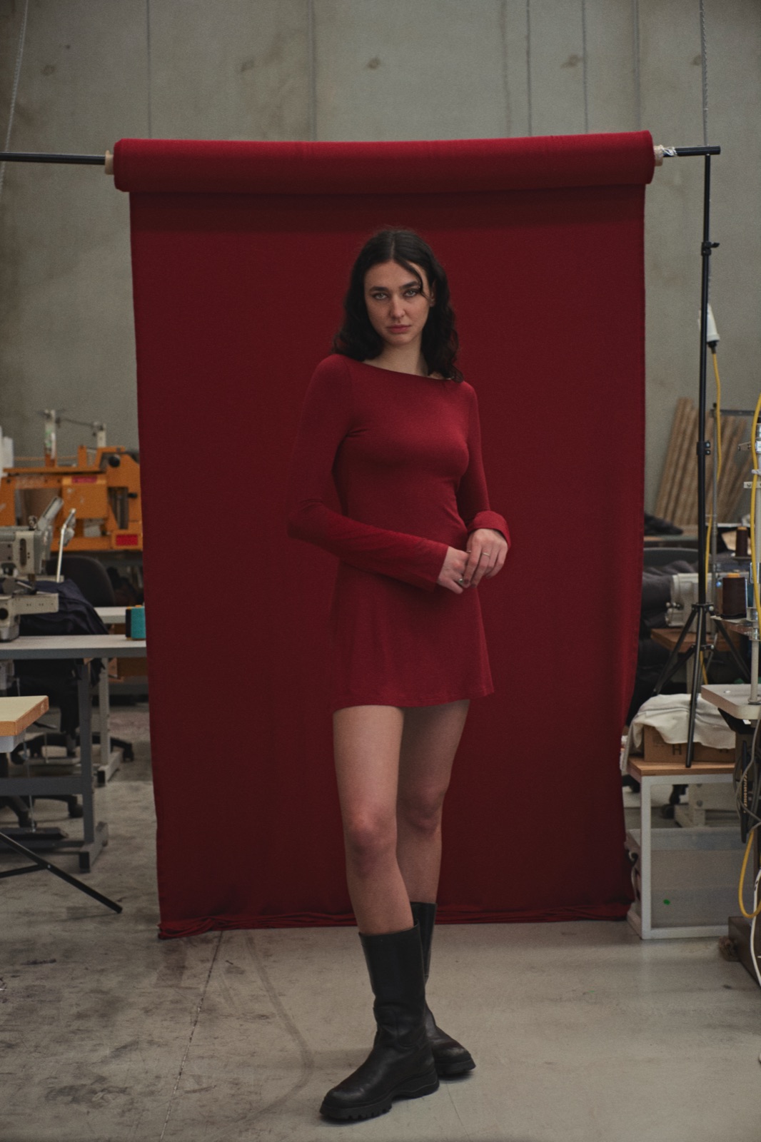 Katja standing in front of a roll of red fabric hung on the factory floor, photographed by Eli Samuel for Australian Stitch.