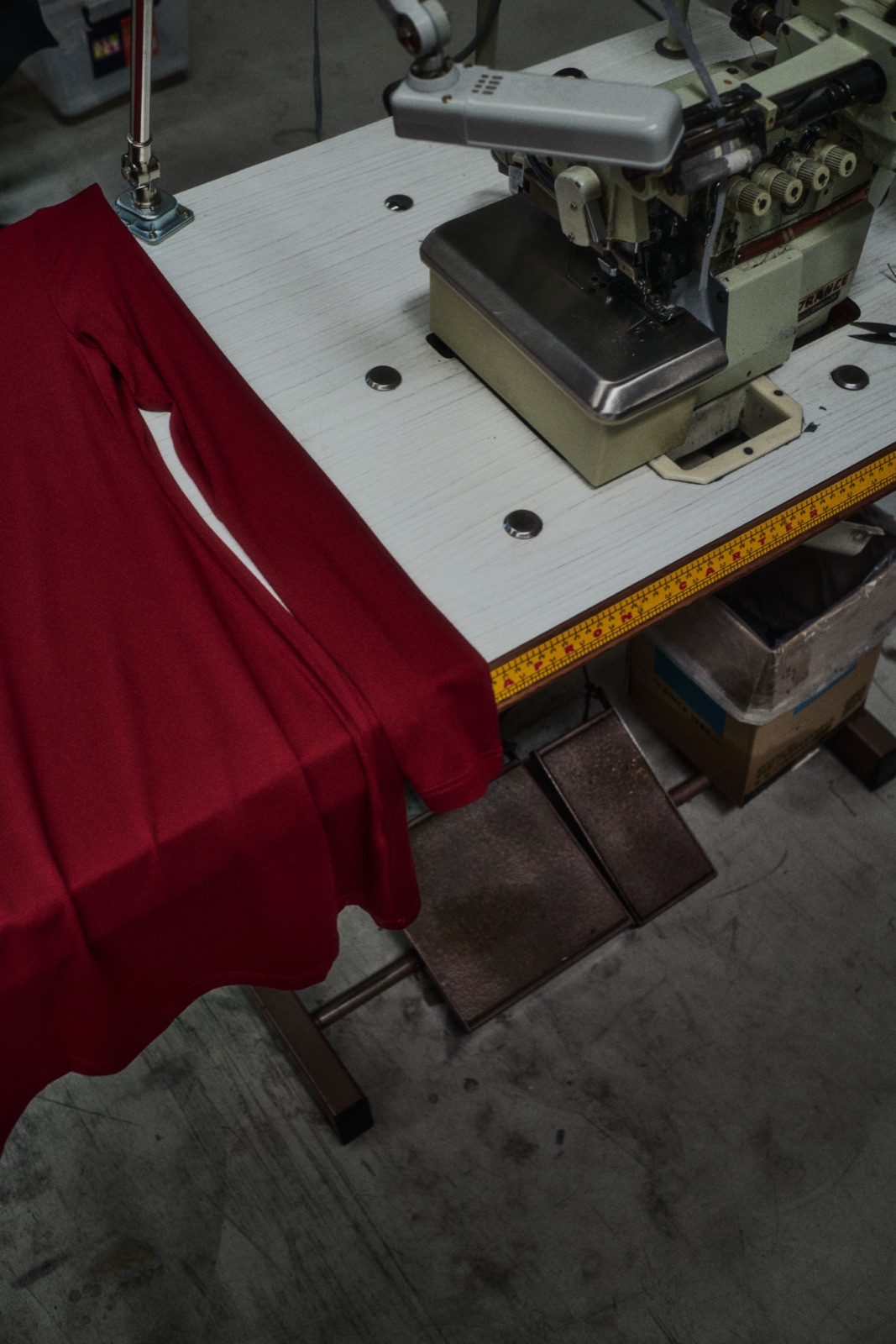 A red garment feeding through an overlocker, photographed by Eli Samuel for Australian Stitch.