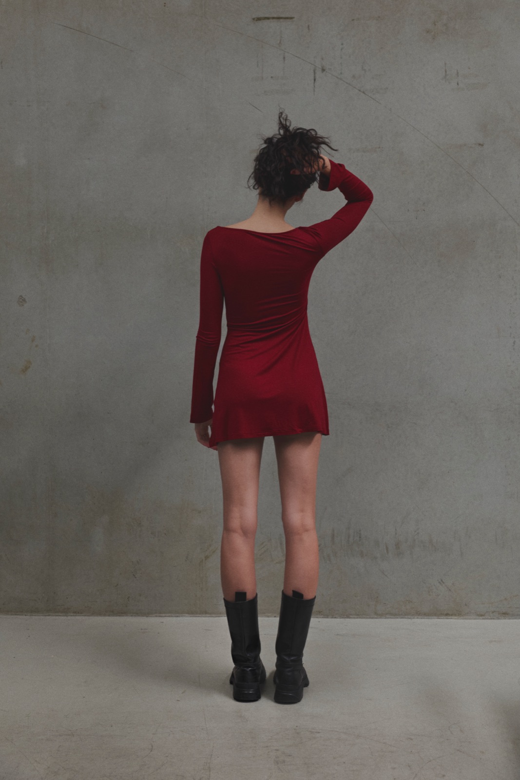 Katja from behind in a red dress with a hand in her hair against concrete, photographed by Eli Samuel for Australian Stitch.