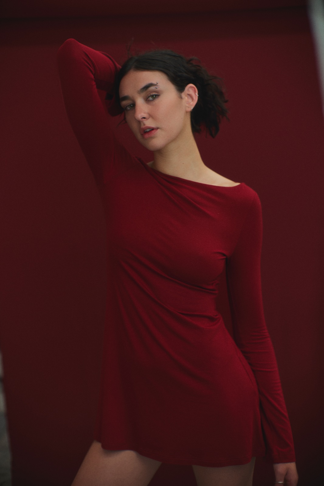 Katja in a red dress with an arm raised against red fabric, photographed by Eli Samuel for Australian Stitch.