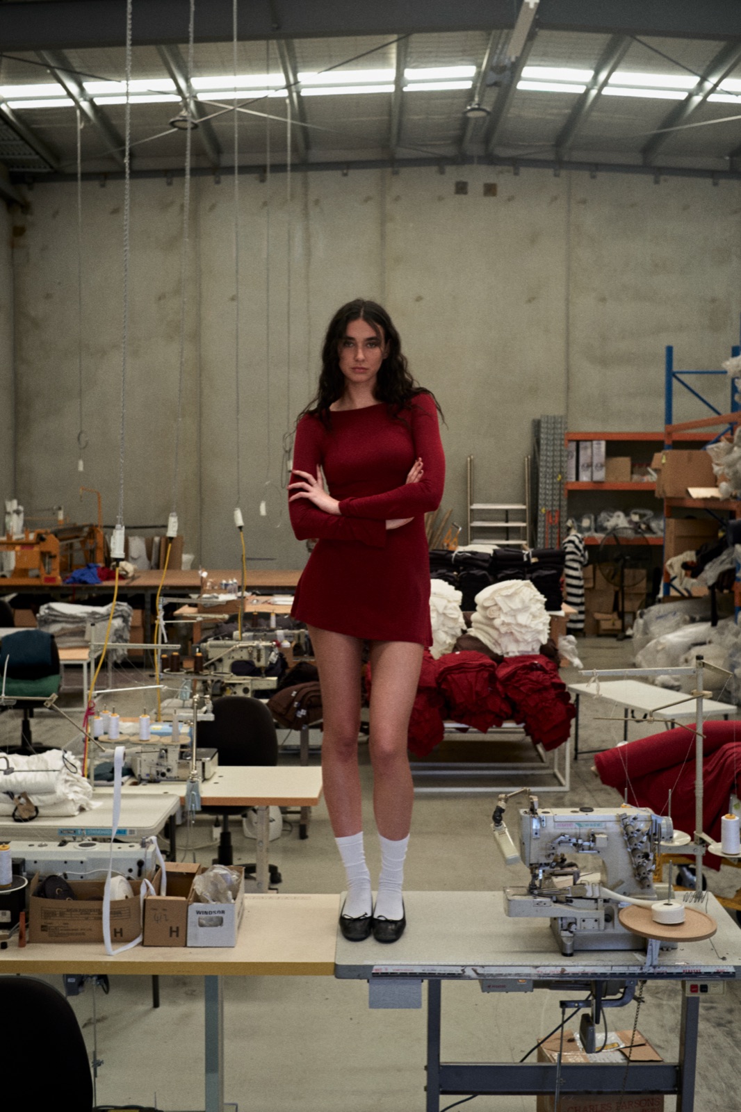 Katja standing on a table in a red dress in the middle of the factory floor, photographed by Eli Samuel for Australian Stitch.