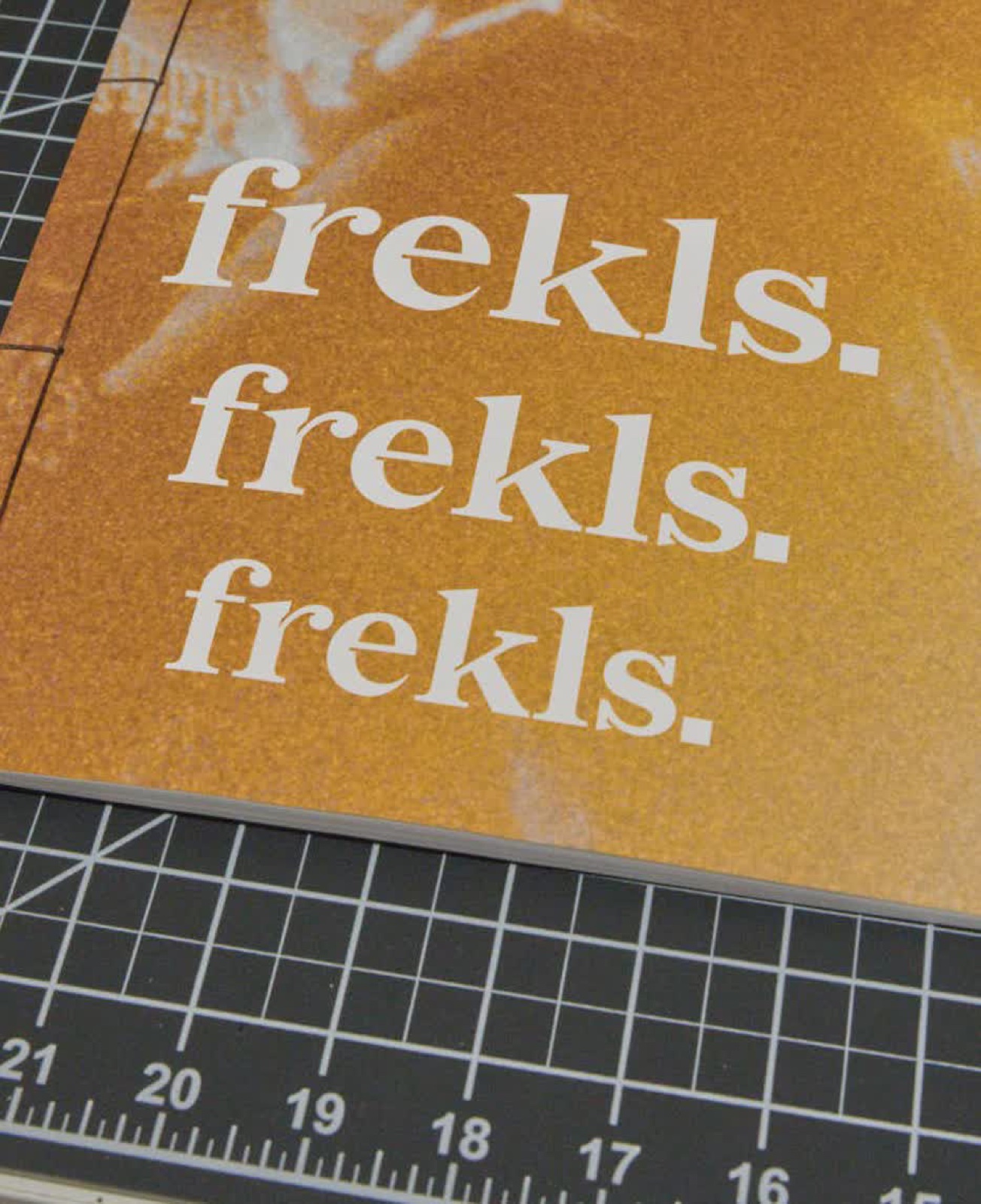 Zine cover with ‘frekls.’ printed three times on gold paper