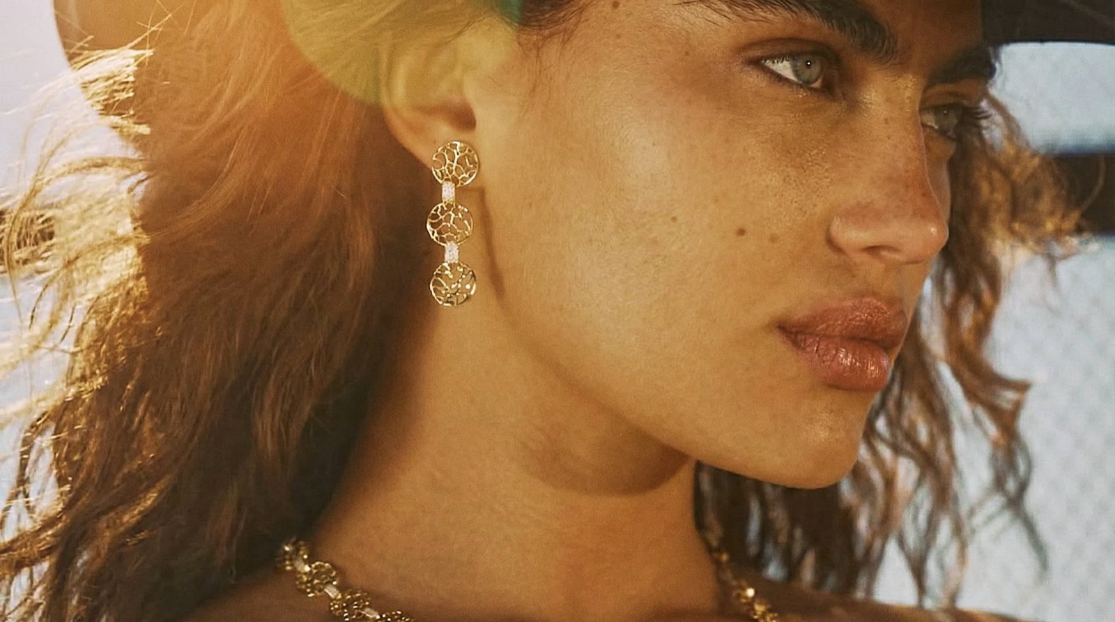 Close-up of gold drop earrings on a model's ear