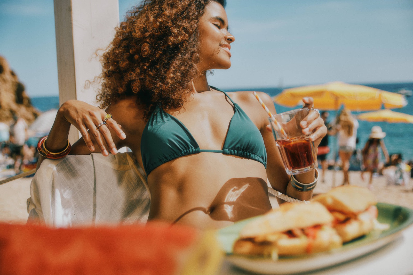 Woman in a green bikini relaxing at a sunlit beach café