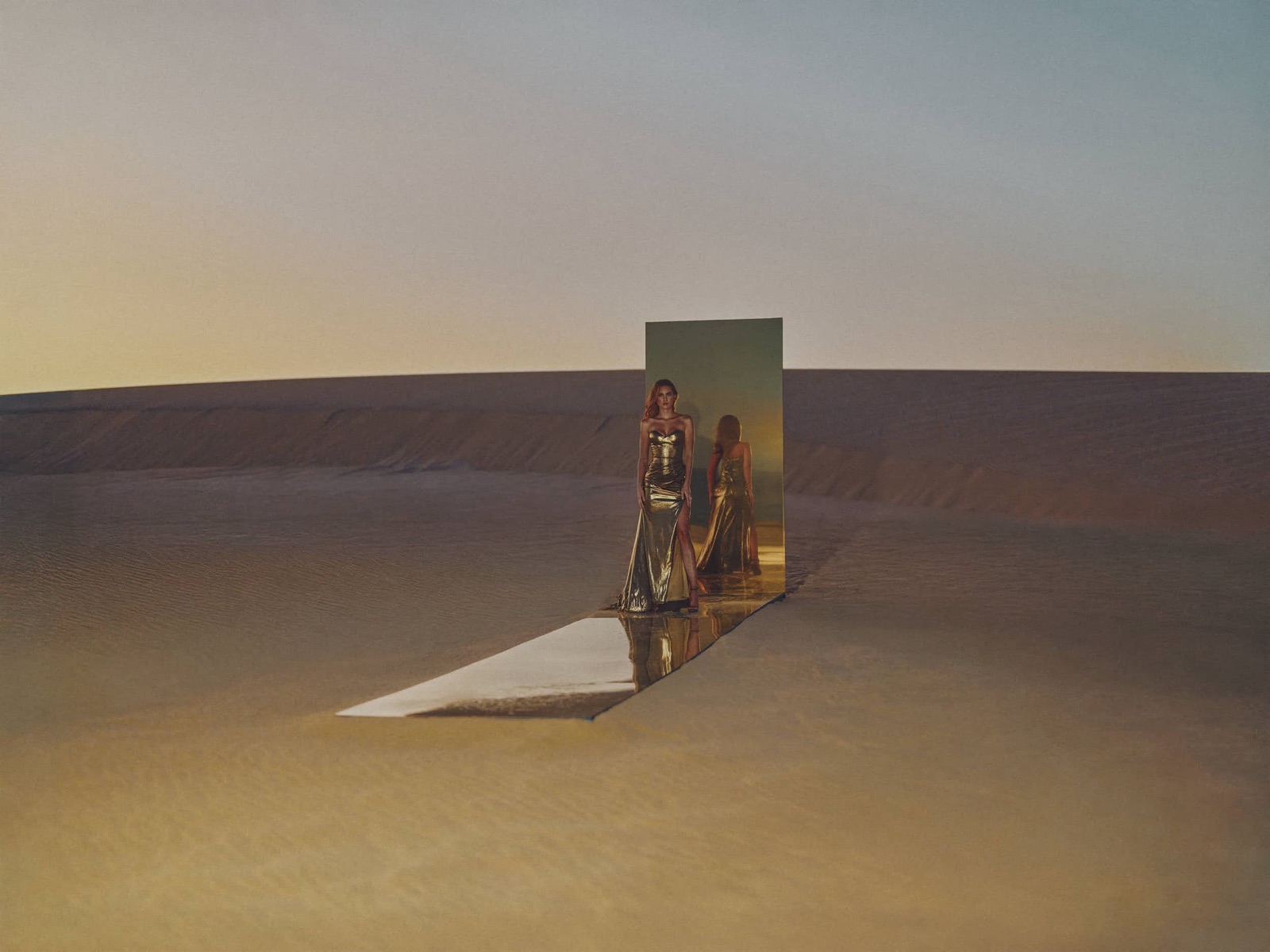 Gold sequined gown reflected in a mirror on a desert dune